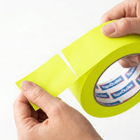 Person easily tearing a strip of neon yellow matte gaffer tape by tapedudes